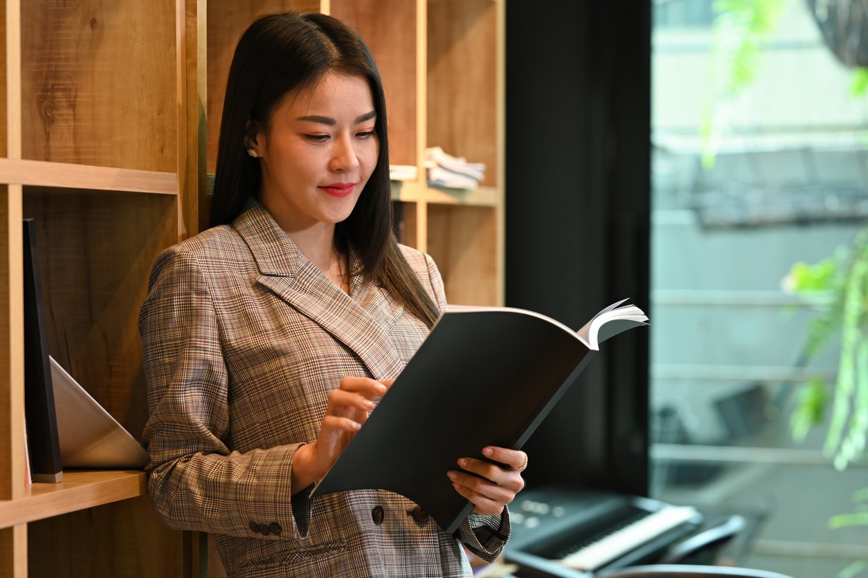Female employee reading book in her suit