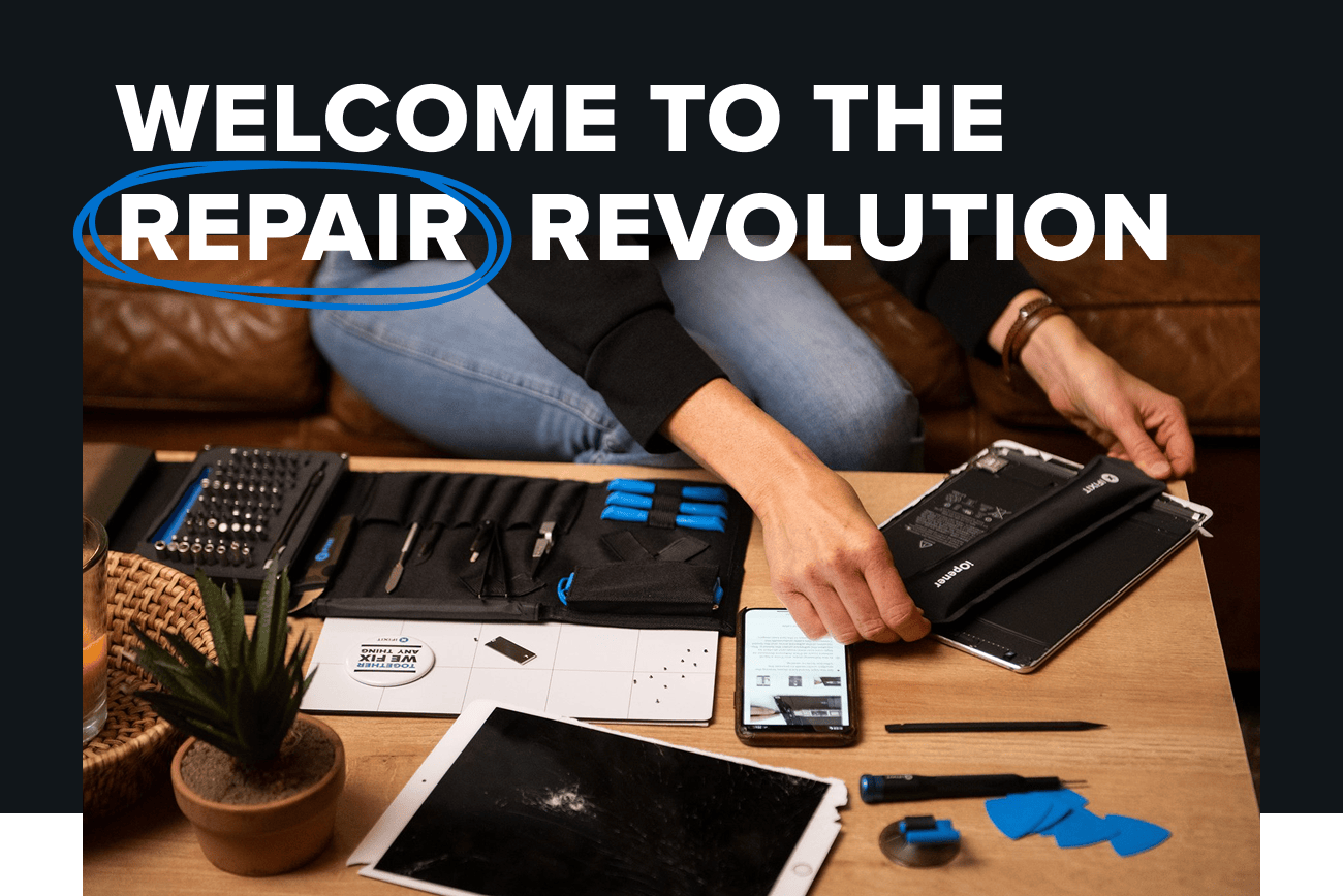 Text: Join the Repair Revolution. Graphic: Lifestyle image showing a person repairing a tablet at a coffee table using the iFixit Pro Tech Toolkit. A phone with repair instructions, several blue tools, and a cracked tablet screen are visible.