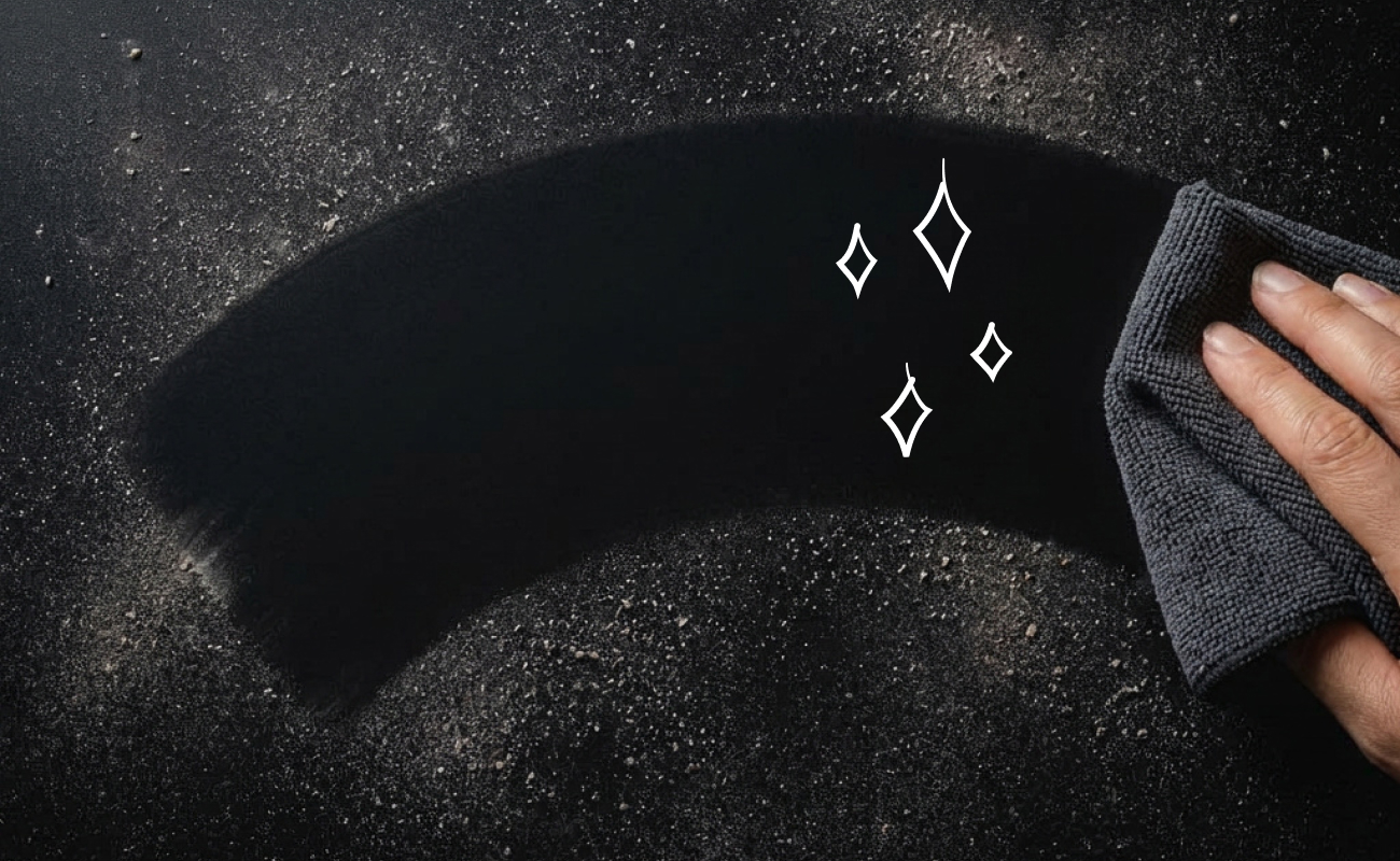 Dusty surface being wiped clean with a microfiber cleaning cloth.