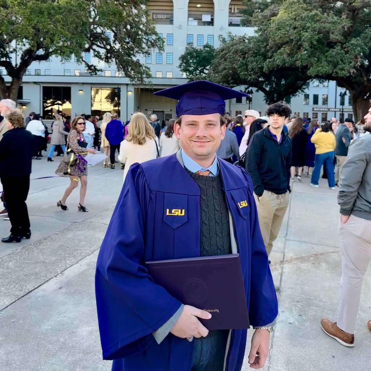 Image of a young man smiling holding a diploma. 