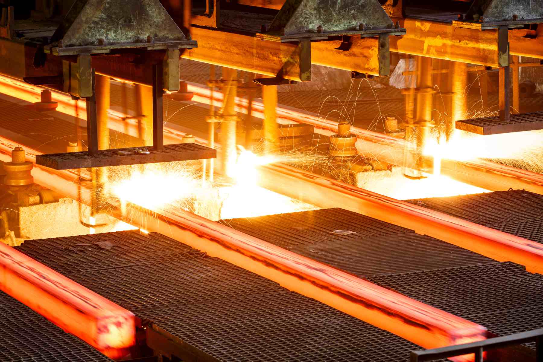 Photo shows close shot of hot steel on conveyor in a steel mill.